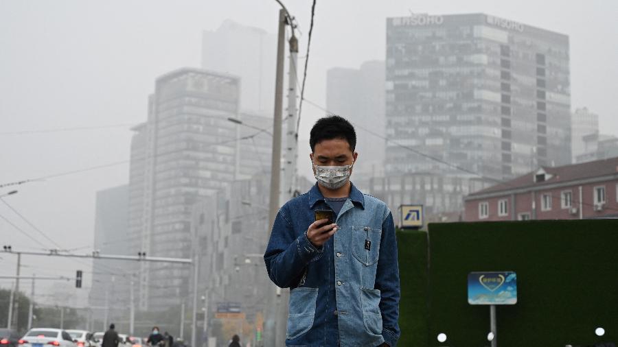 05.nov.2021 - Homem caminha em uma rua de Pequim em dia de intensa poluição - GREG BAKER / AFP