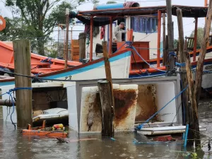 Com casas inundadas, pescadores de Pelotas decidem morar dentro de barcos