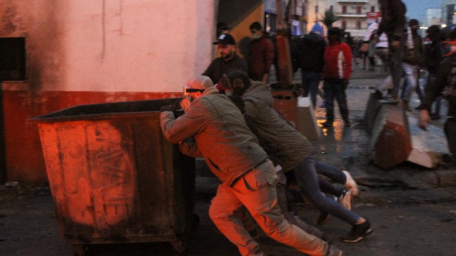 Em Trípoli, manifestantes empurram um contêiner de lixo durante protesto contra o lockdown no Líbano - Omar Ibrahim/Reuters