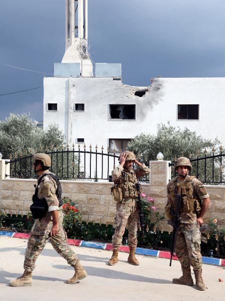 Membros do exército libanês caminham perto de uma mesquita danificada após bombardeio em Dhayra, perto da fronteira com Israel, em 11 de outubro