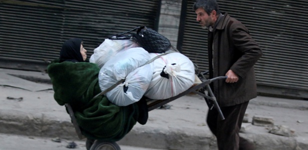 Homem carrega idosa e seus pertences durante fuga de Aleppo, na Síria - Abdalrhman Ismail/ Reuters