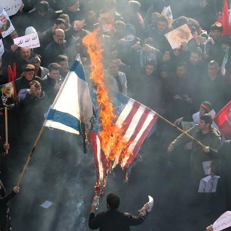 Manifestantes queimam as bandeiras de Israel e dos Estados Unidos durante o funeral do general irainano Qassim Suleimani, em Teerã - ATTA KENARE/AFP