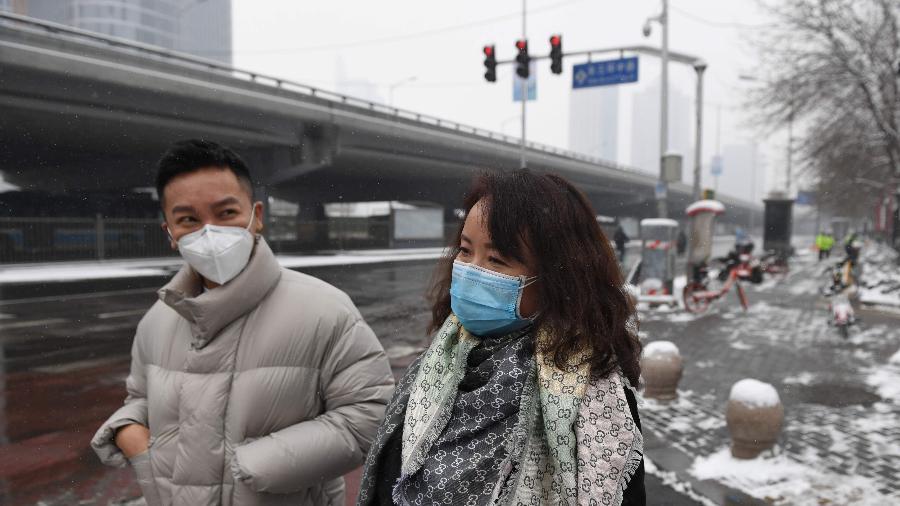 06.fev.2020 - Pessoas usam máscaras para circular numa rua deserta em Pequim - Greg Baker/AFP