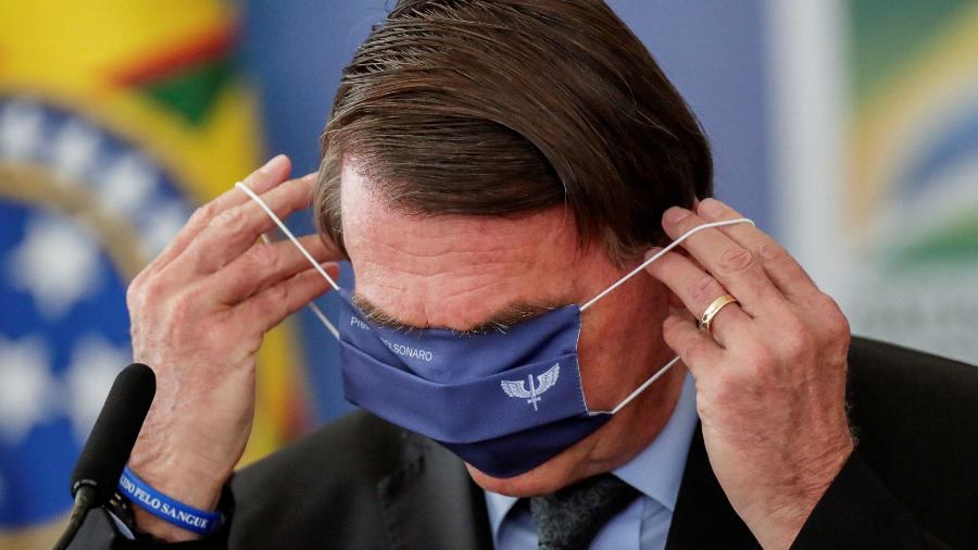 O presidente Jair Bolsonaro coloca máscara durante evento no Planalto, nesta segunda (22) - Ueslei Marcelino/Reuters