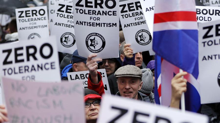 8.abr.2018 - No Reino Unido, manifestantes levantam cartazes contra supostas políticas antissemitas na estrutura governamental. Nas placas, os dizeres: "Tolerância zero ao antissemitismo" - AFP