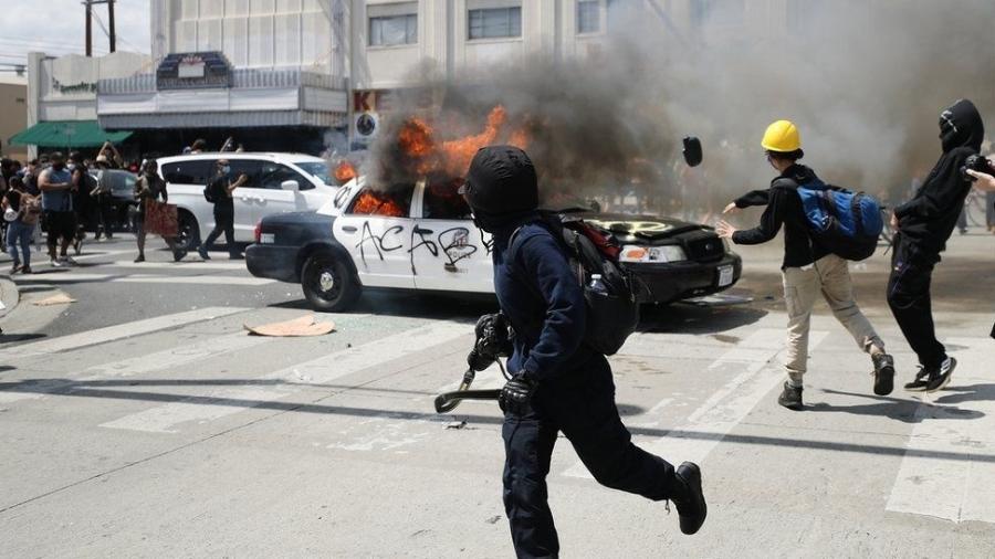 Oficiais da tropa de choque e manifestantes que atearam fogo em viaturas entraram em confronto em Los Angeles, na Califórnia - Getty Images