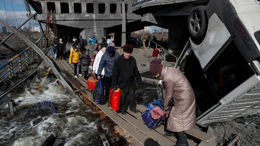 Pessoas atravessam rio Irpin ao lado de uma ponte destruída, em meio ao ataque da Rússia à Ucrânia - Valentyn Ogirenko/Reuters