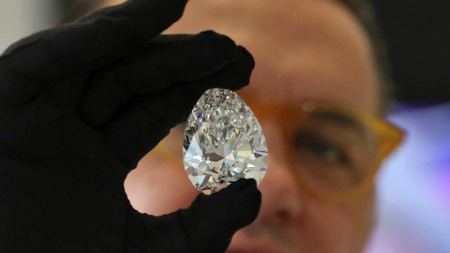 Funcionário da equipe da casa de leilões Christie"s exibe o diamante gigante apelidado de "The Rock", em Dubai - Karim SAHIB / AFP