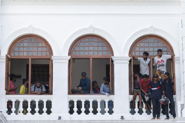 Jul 13.22 - Protesters look out of windows after entering Sri Lankan Prime Minister Ranil Wickremesinghe's office building in Colombo, Sri Lanka, amid the country's economic crisis - ADNAN ABIDI/REUTERS - ADNAN ABIDI/REUTERS