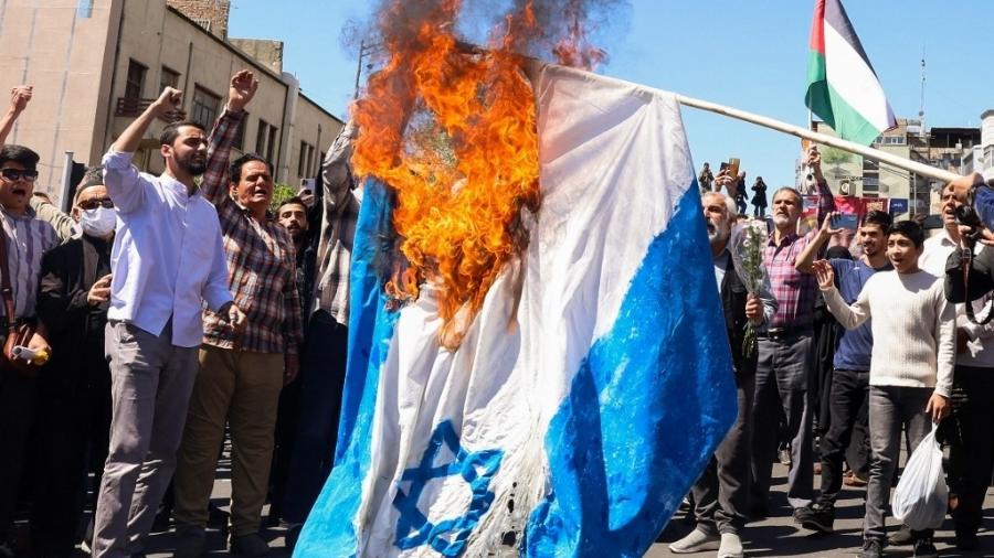 05.abr.24 - Manifestantes queimam uma bandeira israelense durante o funeral de sete membros do Corpo da Guarda Revolucionária Islâmica mortos em um ataque na Síria