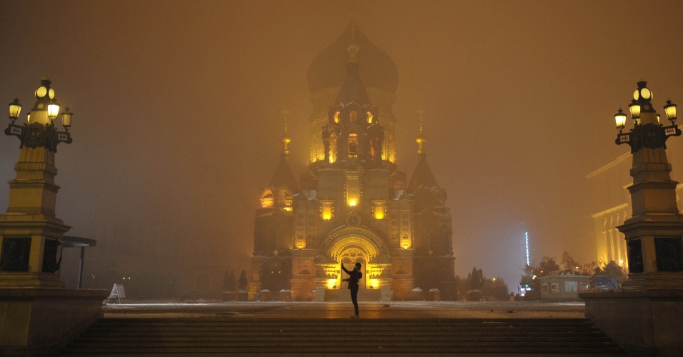 11.nov.2015 - Uma pessoa tira fotos na praça em frente de uma igreja na cidade de Harbin com poluição atmosférica, na China