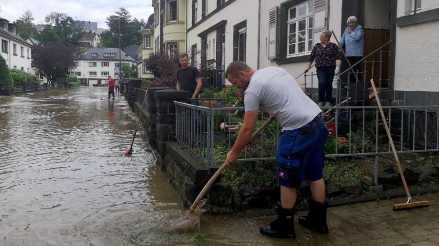 Um homem tenta remover água de uma casa em uma rua inundada em Mayen, oeste da Alemanha - Michelle FITZPATRICK / AFP