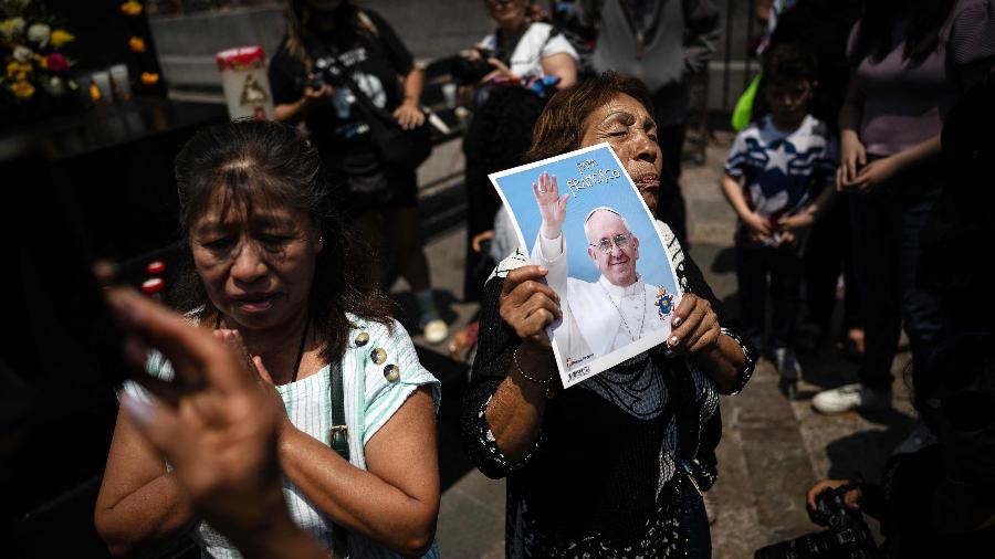Um fiel segura um pôster do falecido Papa Francisco na Basílica de Guadalupe, na Cidade do México, durante um culto em sua morte em 21 de abril de 2025 - CARL DE SOUZA/AFP