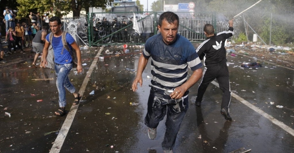 16.set.2015 - Imigrantes são atingidos por jatos de água disparados pela polícia húngara, em Röszke, na fronteira com a Sérvia. A polícia usou gás lacrimogêneo e canhões de água em centenas de imigrantes que protestavam por não conseguir atravessar a fronteira