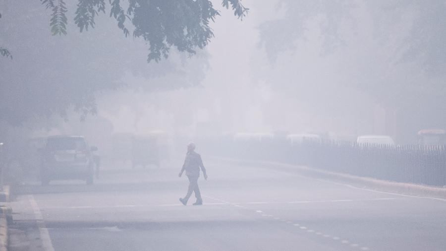 Homem cruza a rua em condições de poluição atmosférica em Nova Délhi  - Jewel Samad/AFP