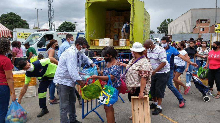 Mulher recebe sacola com alimentos na Ceagesp - Marcelo Oliveira/UOL