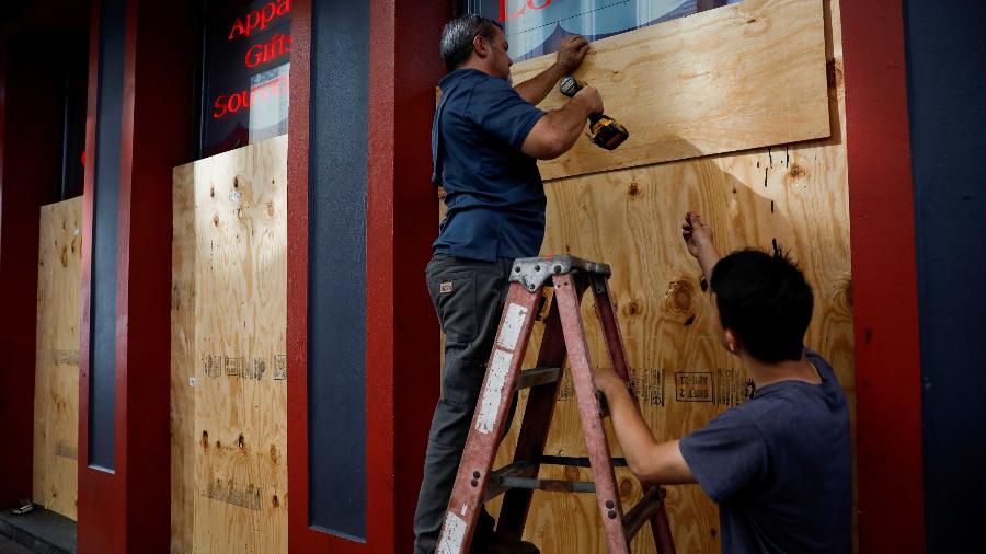Trabalhadores colocam tapumes de madeira para proteger as vitrines de uma loja do furacão Ida, em New Orleans, nos EUA - Marco Bello/Reuters