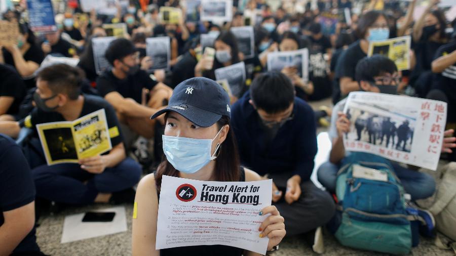Manifestantes seguram cartazes na área de chegada do Aeroporto Internacional de Hong Kong para que turistas leiam - Thomas Peter/Reuters