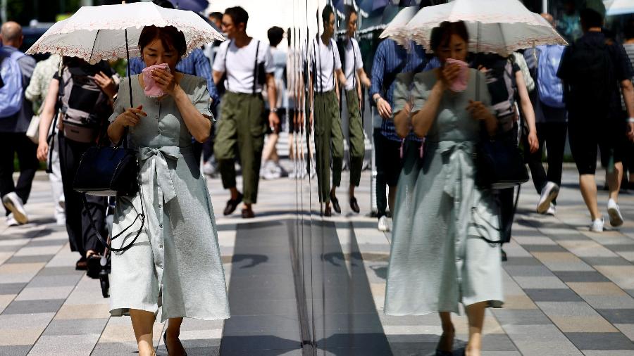 Mulher se protege do sol com uma sombrinha em uma rua de Tóquio, Japão, 9 de julho de 2024