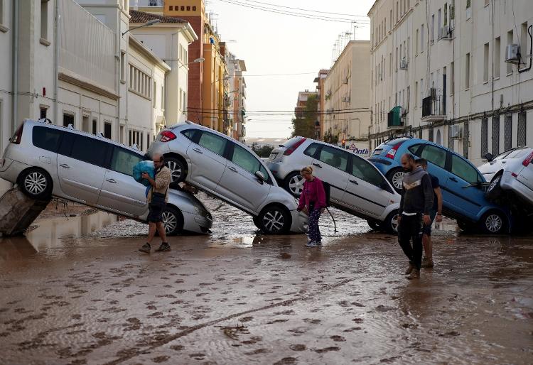 30.out.2024 - Moradores passam por carros empilhados após enchentes mortais no bairro De La Torre, em Valência, ao sul de Valência, leste da Espanha