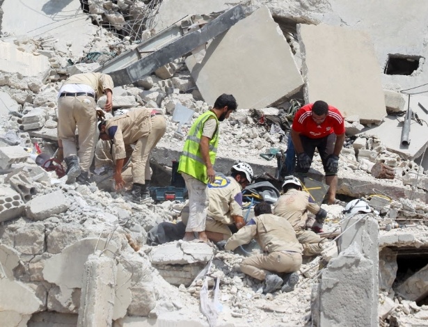 Equipes da defesa civil e voluntários procuram por sobreviventes sob os escombros após a queda de um avião militar em Ariha, na Síria, nesta segunda-feira (3)