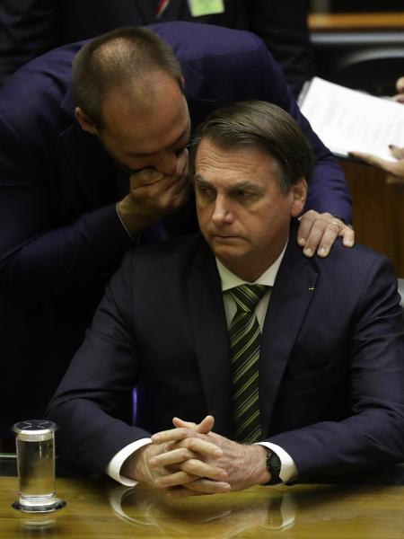 15.jul.2019 - Eduardo Bolsonaro (PSL-SP) sussurra no ouvido do pai durante sessão solene na Câmara - GABRIELA BILó/ESTADÃO CONTEÚDO