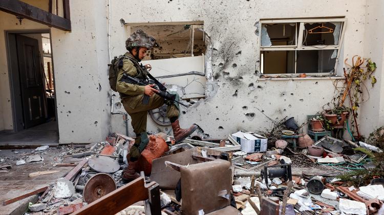 Soldado de Israel em destroços de casa no kibbutz Be-eri, no sul do país, após ataque do Hamas