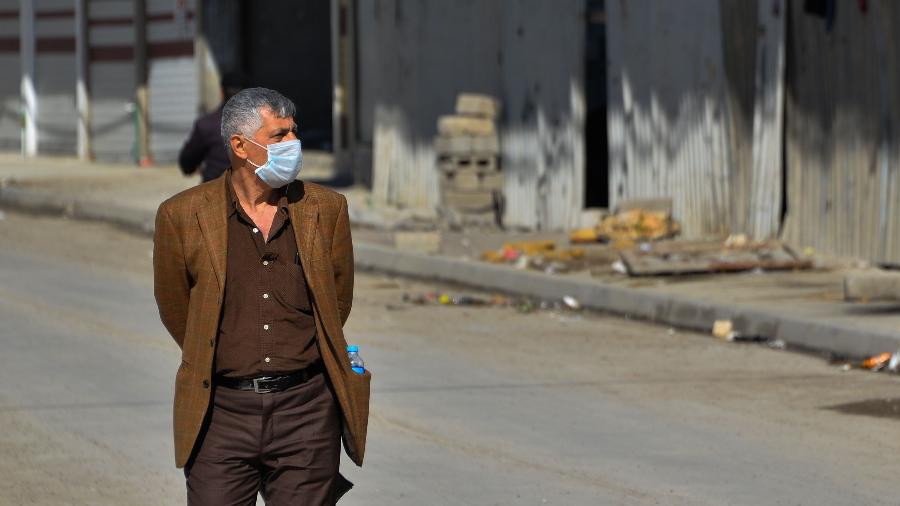 3.mar.2020 - Homem usa máscara ao andar em rua deserta na cidade de Mosul, no Iraque, em meio a temores da propagação do coronavírus pelo país - Zaid Al-Obeidi/AFP