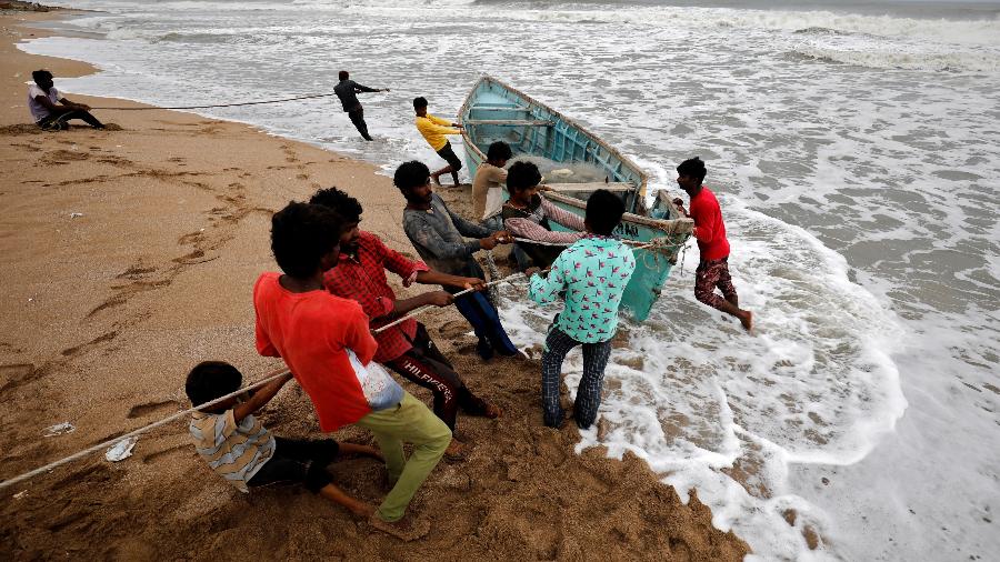 Pessoas tentam resgatar um barco de pescaria em uma praia em Gujarat, durante passagem do ciclone Tauktae, na Índia - REUTERS/Amit Dave