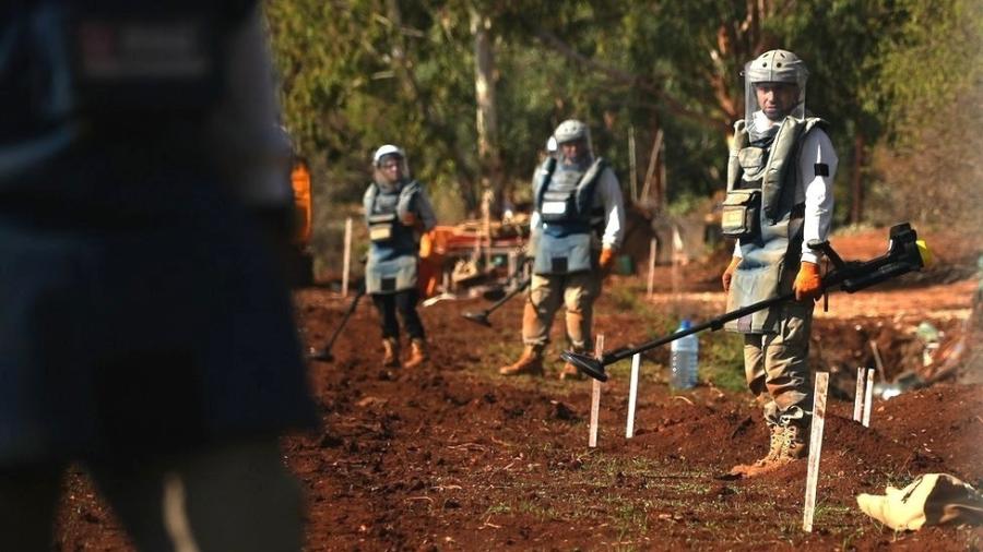 Equipes de desativação de minas terrestres no Líbano, com seu forte equipamento de proteção, começam seu trabalho cedo de manhã para evitar temperaturas sufocantes - BBC