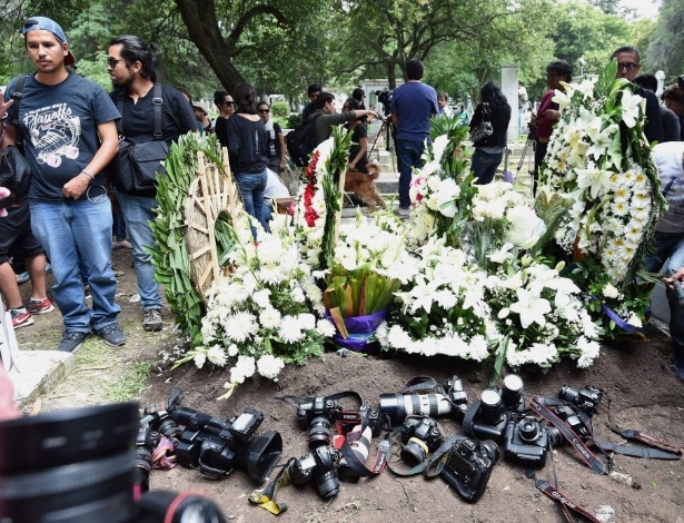 Colegas do fotógrafo mexicano Ruben Espinosa, morto em 31 de julho, colocam suas câmeras ao lado de sua sepultura no cemitério de Dolores, na Cidade do México - Alfredo Estrella/AFP
