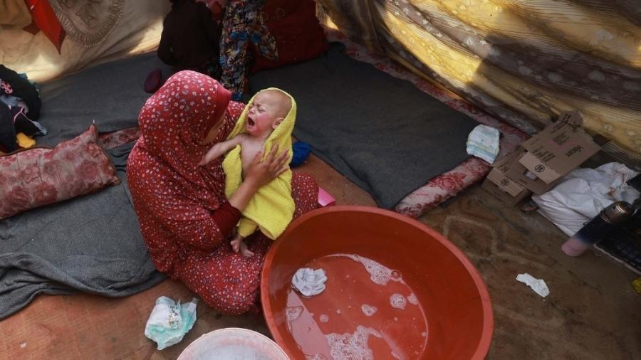 Mulher seca bebê em um acampamento para palestinos que precisaram deixar suas casas por causa de bombardeios