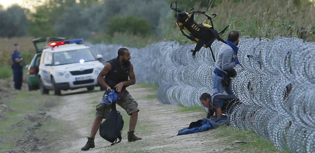 26.ago.2015 - Sob olhares da polícia húngara, imigrantes sírios tentam pular cerca de arame farpado na fronteira entre a Sérvia e a Hungria, em Roszke - Laszlo Balogh/Reuters
