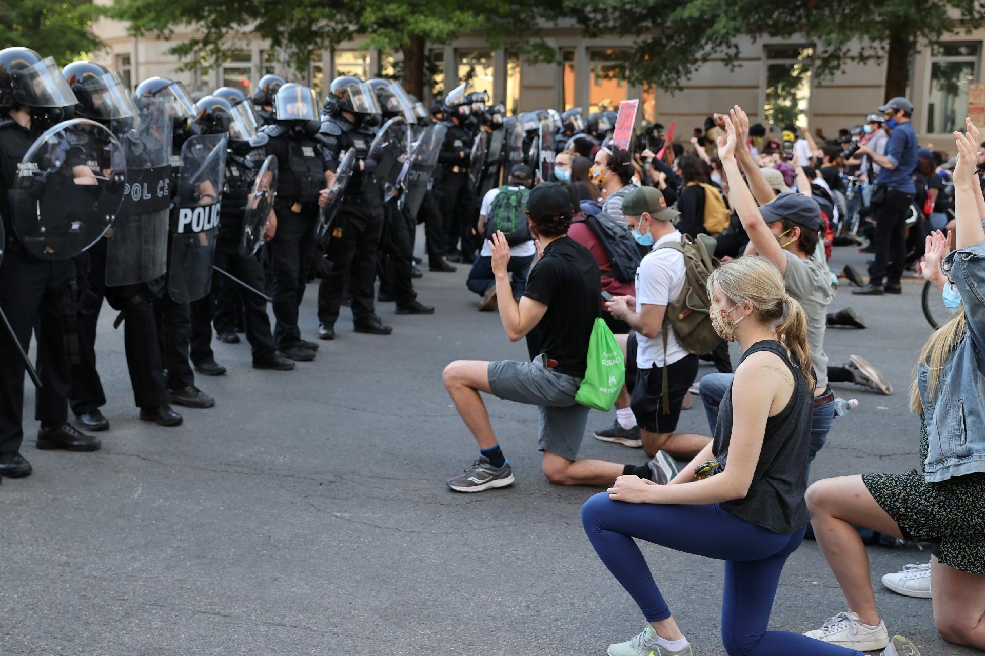 Manifestantes se ajoelham diante de oficiais da divisão do Serviço Secreto dos EUA durante protestos contra a morte de George Floyd, perto da Casa Branca em Washington DC - JONATHAN ERNST/REUTERS
