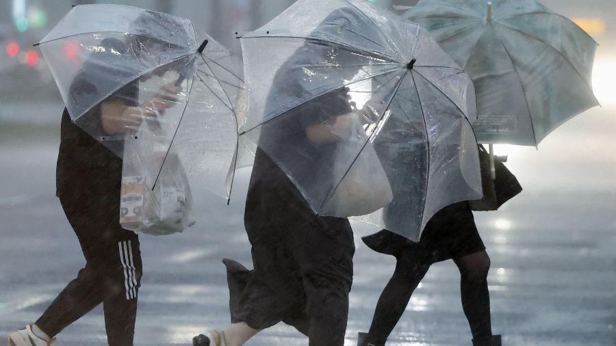 Pedestres segurando guarda-chuvas lutam contra ventos fortes e chuvas pesadas causadas pelo Tufão Shanshan em Kagoshima, sudoeste do Japão, em 28 de agosto de 2024