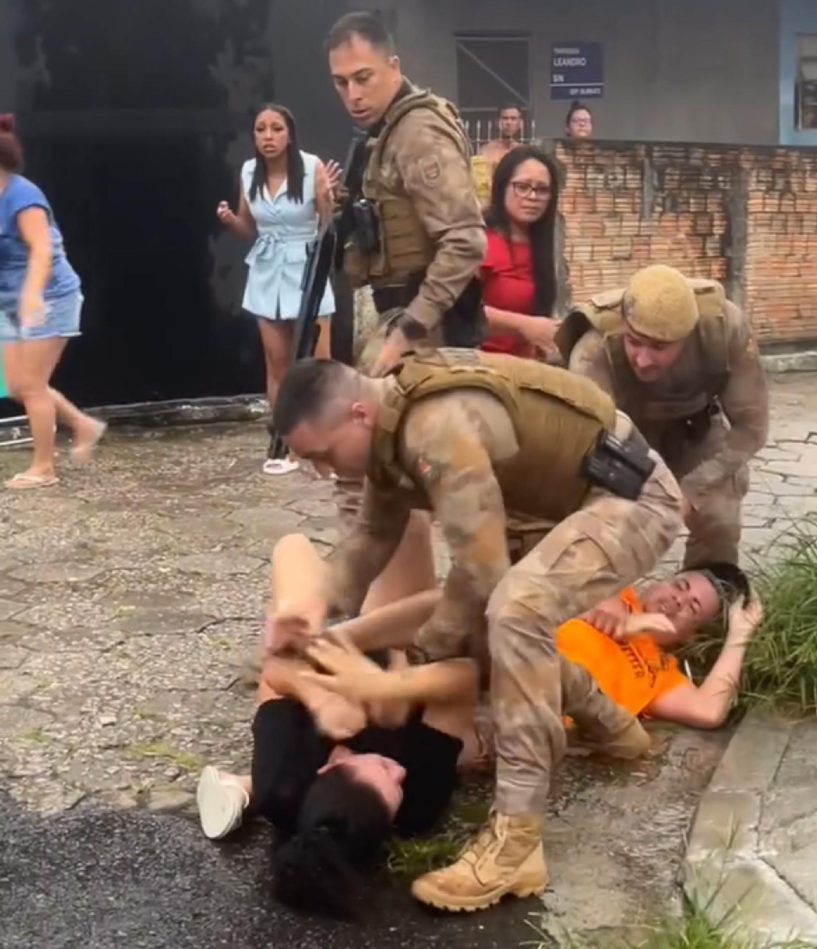 Momento em que policial dá um tapa no rosto de uma mulher imobilizada - undefined