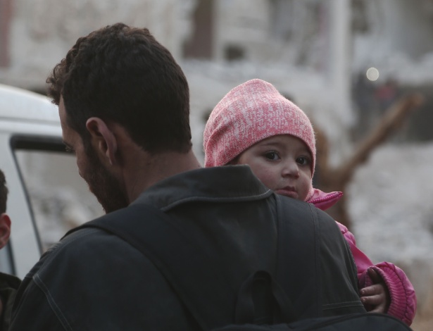Criança síria e seu pai na noite de ontem, se preparando para deixar Ghouta Oriental - Abdulmonam Eassa/AFP Photo