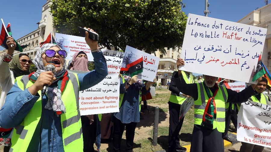 16.abr.2019 - Manifestantes líbios seguram cartazes contra o que chamam de intervenção estrangeira na Líbia, durante um protesto em frente ao município de Trípoli - Mahmud Turkia/AFP