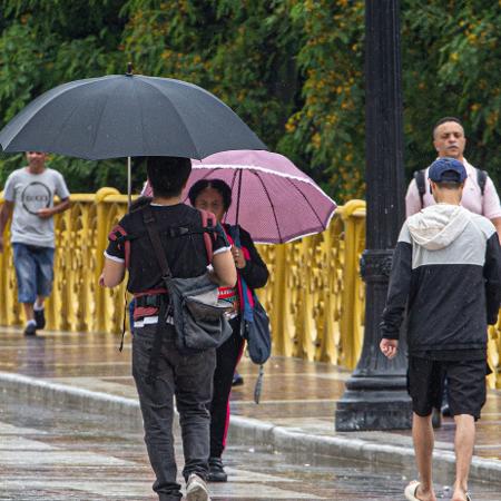 Pedestres se protegem da chuva na região central da cidade de São Paulo - BRUNO ESCOLASTICO/E.FOTOGRAFIA/ESTADÃO CONTEÚDO