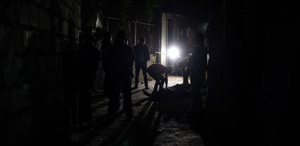 Policiais investigam corpo de um suposto usuário de drogas morto por atiradores em Manila - Noel Celis/ AFP