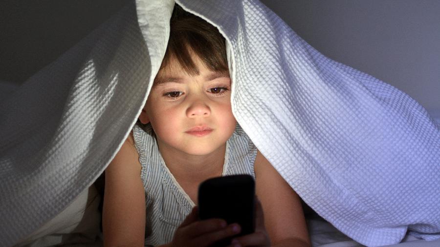 Criança usa smartphone Android na cama antes de ir dormir - Getty Images/iStockphoto