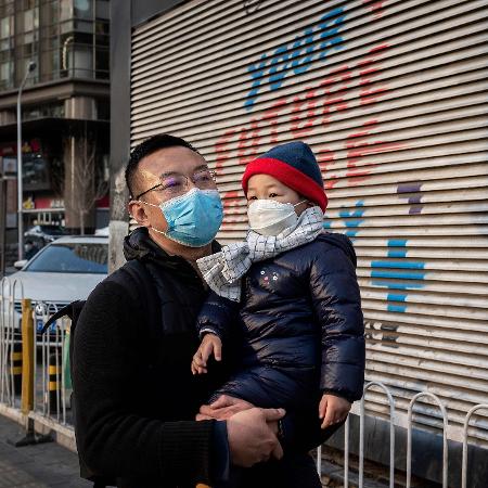 Homem e criança usam máscara como medida preventiva contra o coronavírus em Pequim, na China - Nicolas Asfouri/AFP