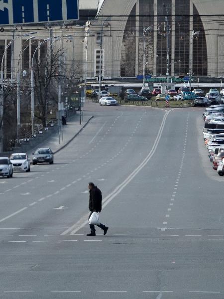 Morador atravessa rua esvaziada durante toque de recolher em Kiev, na Ucrânia, na manhã de domingo (27) - Carlos Barria/Reuters