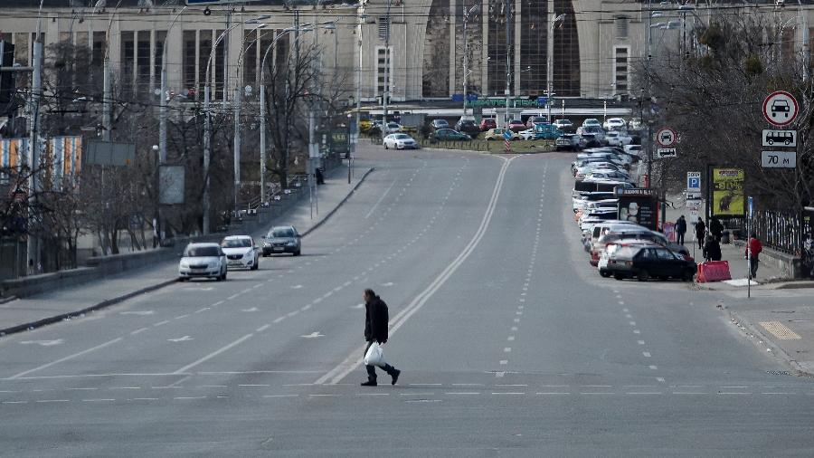 Morador atravessa rua esvaziada durante toque de recolher em Kiev, na Ucrânia, na manhã de domingo (27) - Carlos Barria/Reuters