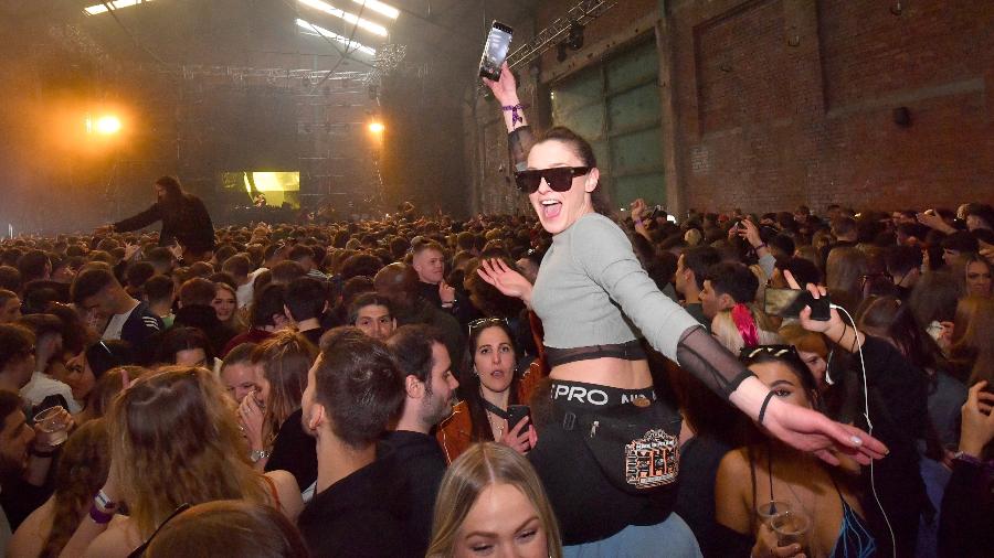 Mulher com um celular na mão durante festa rave em Liverpool - Anthony Devlin/Getty Images