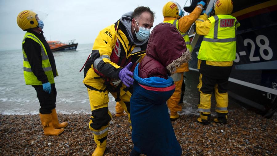 24.nov.2021 - Imigrantes são ajudados a desembarcar em um barco salva-vidas em uma praia em Dungeness, na costa sudeste da Inglaterra,pós serem resgatados durante a travessia do Canal da Mancha - Ben Stansall/AFP