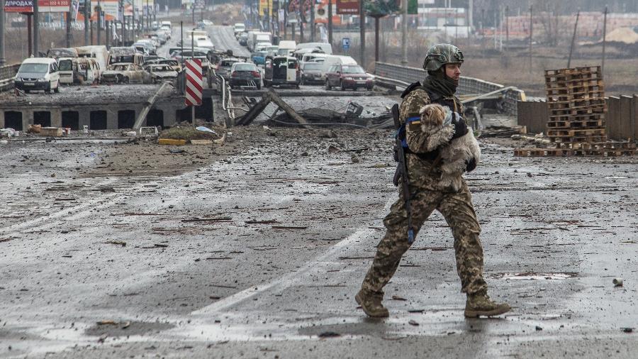 31.mar.2022 - Soldado da Ucrânia carrega cachorro perto de ponte destruída em Irpin, na região de Kiev, em meio à guerra com a Rússia - Oleksandr Ratushniak/Reuters