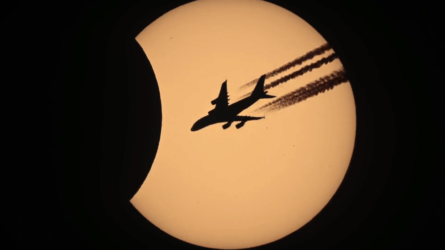 Eclipse solar de 25/10 visto de Wolfurt, na Áustria, no momento em que um avião, indo da França a Dubai, cruzava o céu - Philipp Salzgeber
