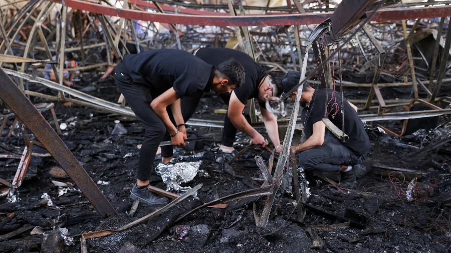 Voluntários buscam desaparecidos nos escombros de salão de festas em Nínive, no Iraque, onde incêndio em festa de casamento deixou mais de 100 mortos
