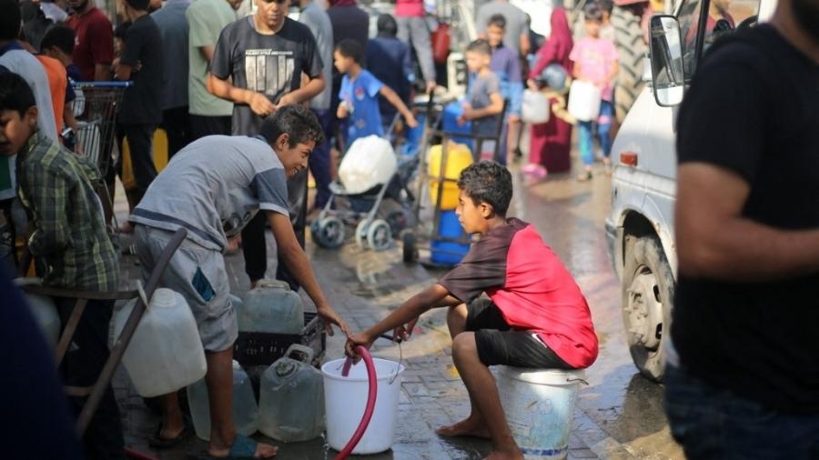 Palestinos deslocados buscam água em um ponto de distribuição no campo de refugiados de Nuseirat, no centro da Faixa de Gaza, em 10 de julho de 2025
